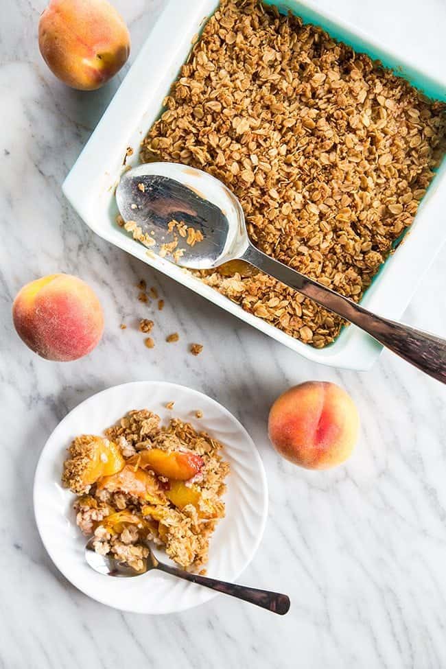 adding oat crisp into the slices of peach in a white plate