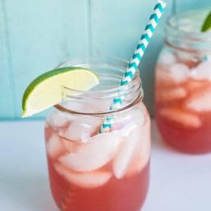 close up Sea Breeze Cocktail in a large mason glass jar topped with ice and garnished with a lime wedge