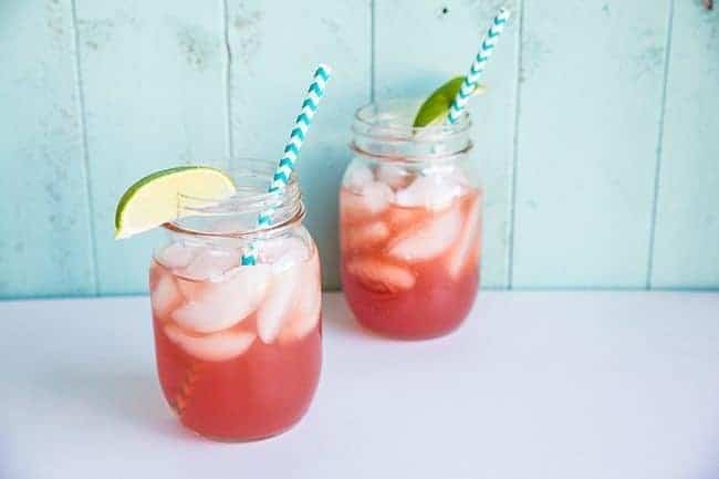 close up Sea Breeze Cocktail in a large mason glass jar topped with ice and garnished with a lime wedge