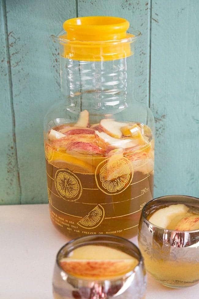 close up of Bourbon Apple Cider Sangria in a pitcher and in roly poly glasses