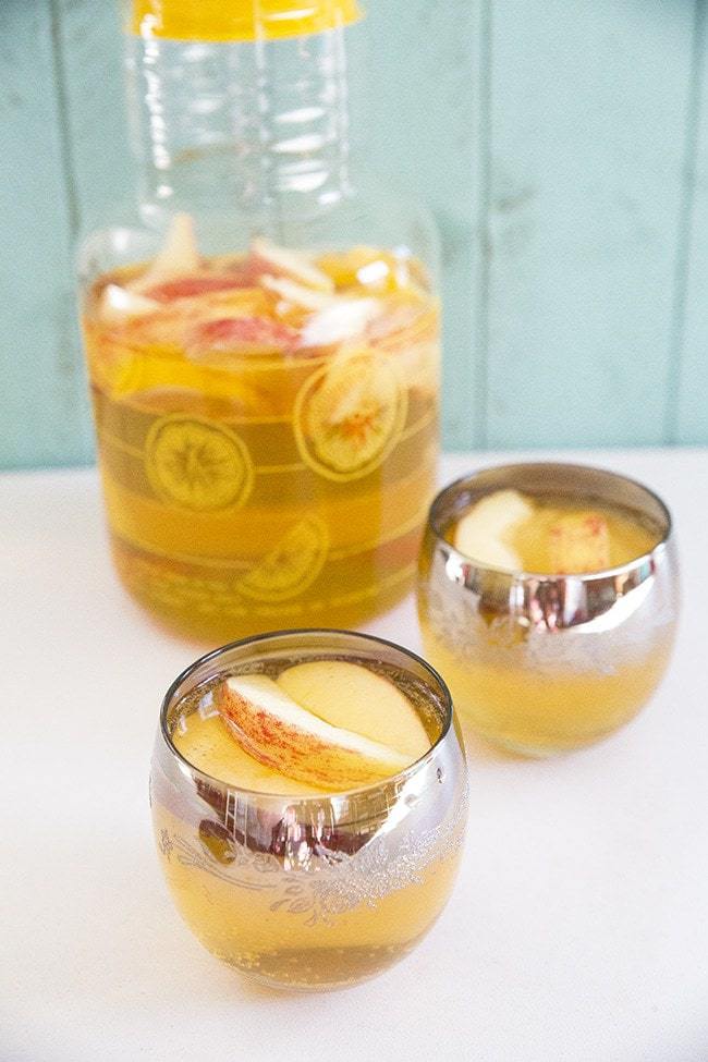 2 roly poly glasses with Bourbon Apple Cider Sangria and a pitcher with it at the back