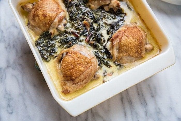 Swiss Chard Chicken with creamy sauce in a baking dish on a marble background