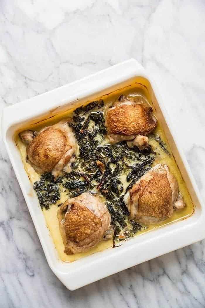 top down shot of baking dish with Creamy Garlic Swiss Chard Chicken on a marble background