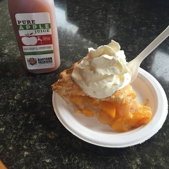 pure apple juice in container and a slice of pie topped with whipped cream in a white small plate