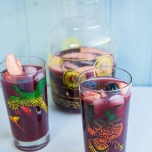 2 vintage glasses with Red Wine Sangria and a large pitcher with lid on background