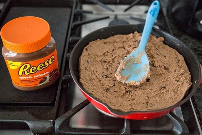 reeses chocolatey peanut cookie dough pressed in skillet, bottle of Reese's spread on the side