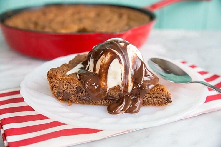 a slice of Reese's Chocolate Chip Skillet Cookie with ice cream melting and chocolate sauce on top