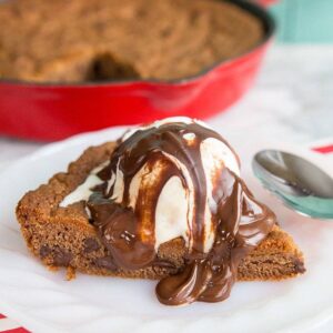 Reese's Chocolate Chip Skillet Cookie with ice cream melting and chocolate sauce on top