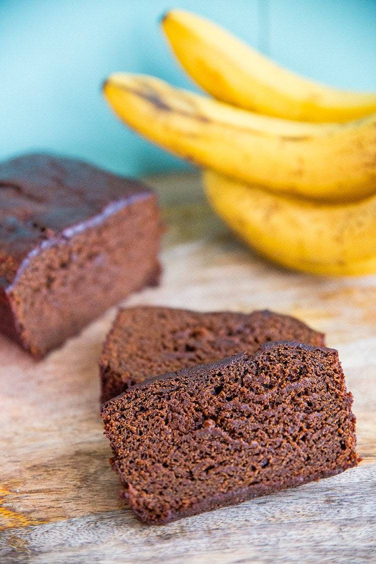 close up slices of Banana Gingerbread Loaf, ripe bananas on background