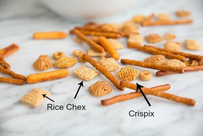 Rice Chex and crispix together with pretzels and nuts on a marble background