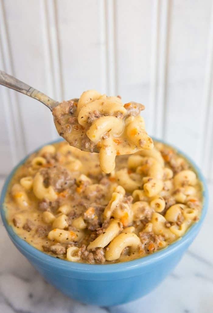 getting a spoon of Crockpot Macaroni Cheeseburger Soup from a blue bowl