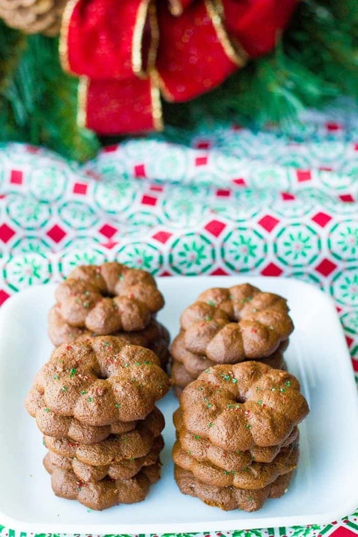 snappy, crunchy little gingersnap cookies in white plate, red Christmas ribbon on background