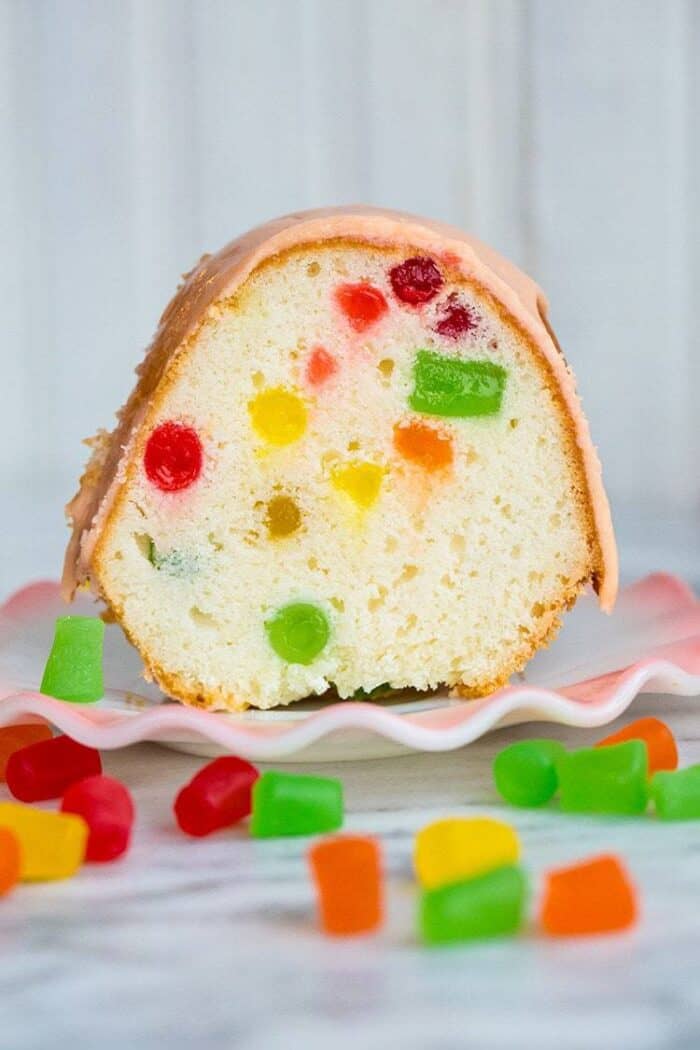 close up slice of Gumdrop Cake in a white dessert plate, some pieces of gumdrops on the table