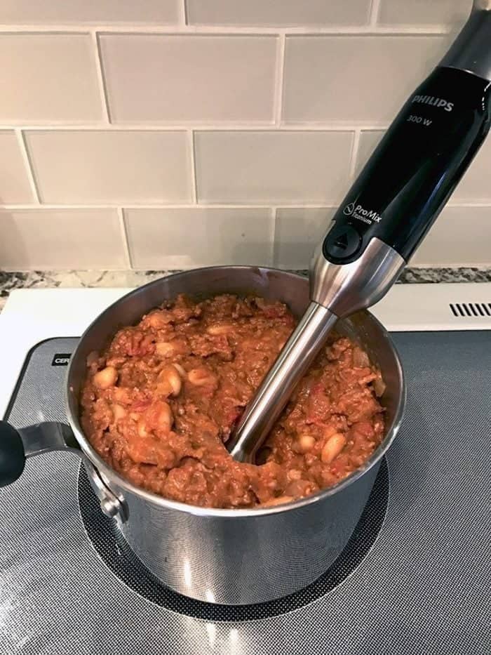 blending up the chili in a small pot using a hand blender