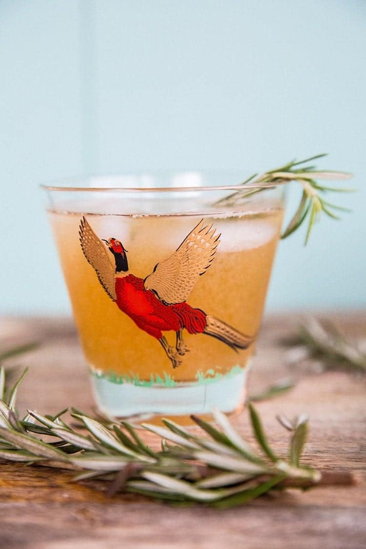 Maple Rosemary Bourbon Sour in a pheasant cocktail glasses with springs of rosemary 