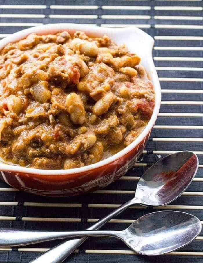 a bowl of White Bean Pumpkin Chili with 2 spoons beside it