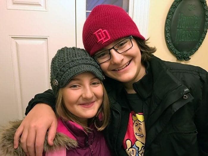 siblings smiling together - girl wearing pink jacket, boy wearing black jacket