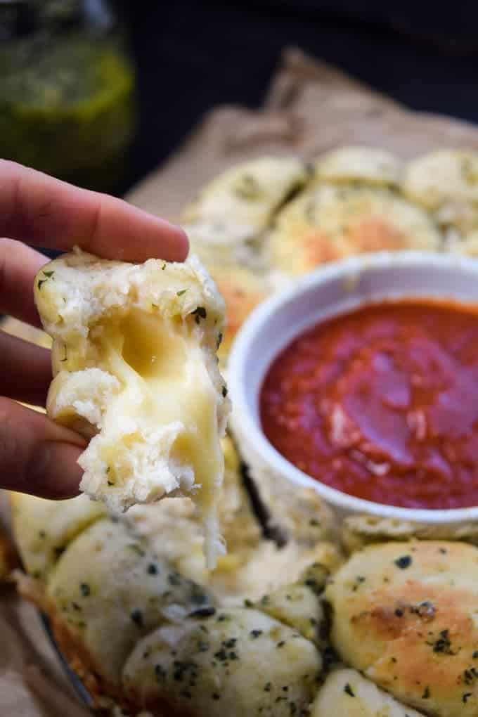 close up Mozza Stuffed Pesto Pizza Monkey Bread with a cup of dipping sauce 