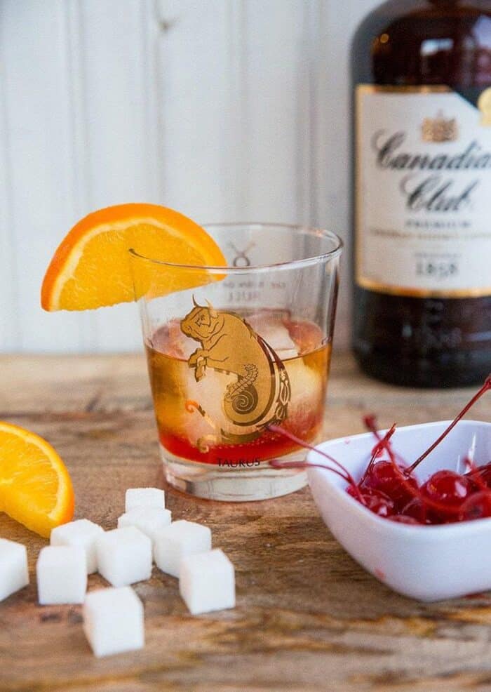 Old Fashioned Cocktail - whisky glass with sugar cube and maraschino cherry Garnish with an orange slice