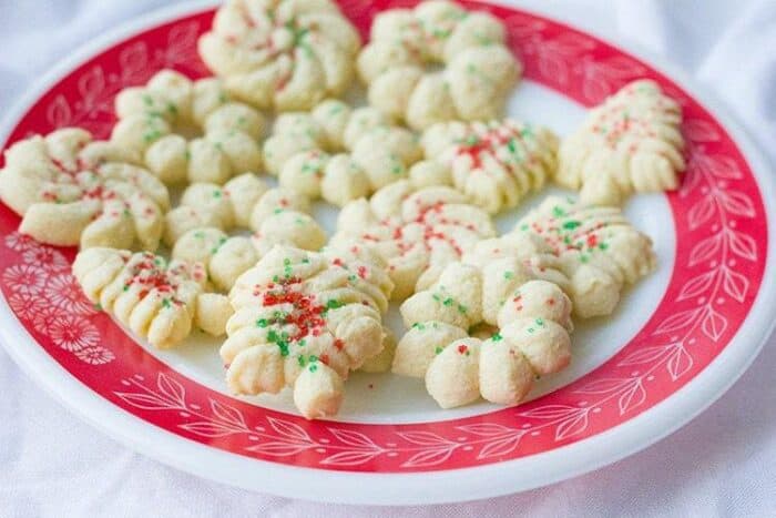 Biscuits Spritz dans une assiette blanche avec un motif rouge sur fond blanc