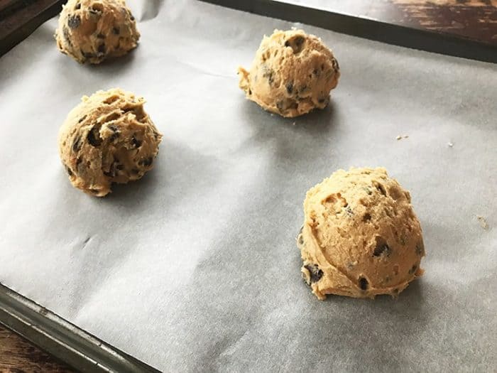 rounded cookie scoops in parchment lined baking sheet