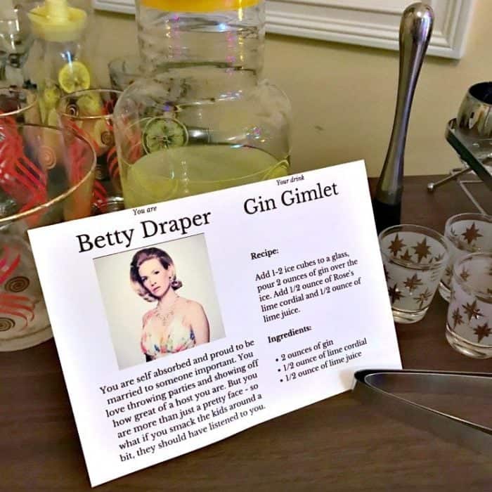 A card with Betty Draper's gimlet details, glasses and jar with cocktail at the back