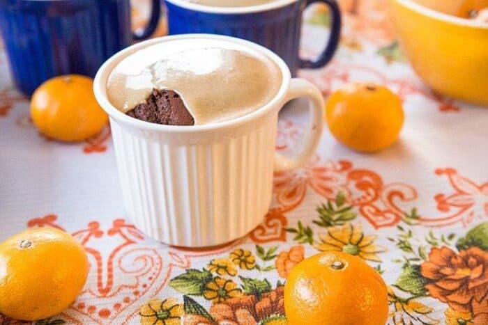 Salted Caramel Gingerbread in a white mug, blue mugs and some fresh oranges on background