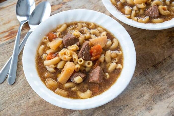 white bowl with Beef Macaroni Soup in beef broth based on wood background