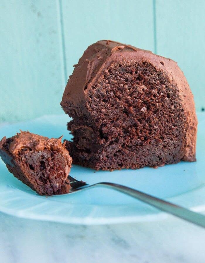 Close up of Chocolate Avocado Bundt Cake Slice with Chocolate Icing in a White Plate and on a Spoon