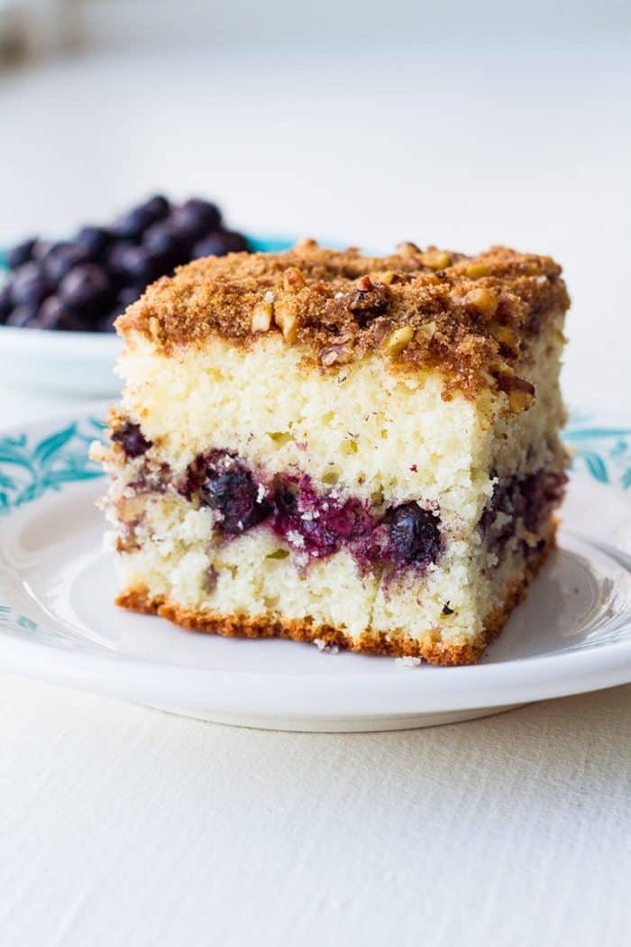 Close up slice of Saskatoon Coffee Cake with blueberries in background