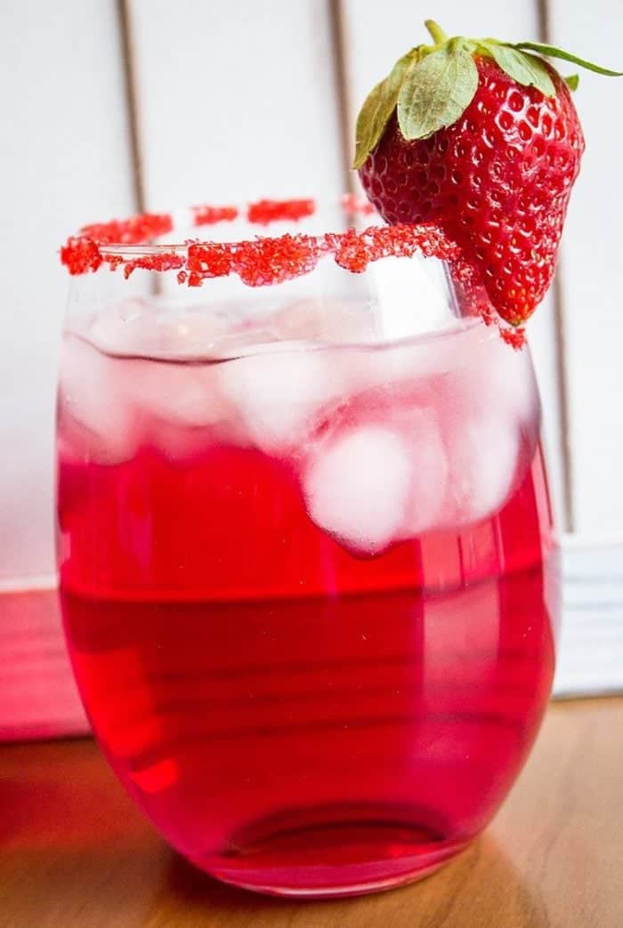 Valentine's Day Cocktail in cocktail glass with rim dipped in red sugar garnished with a fresh strawberry