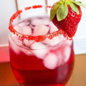 Valentine's Day Cocktail in cocktail glass with rim dipped in red sugar garnished with a fresh strawberry