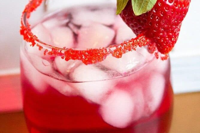 Valentine's Day Cocktail in cocktail glass with rim dipped in red sugar garnished with a fresh strawberry