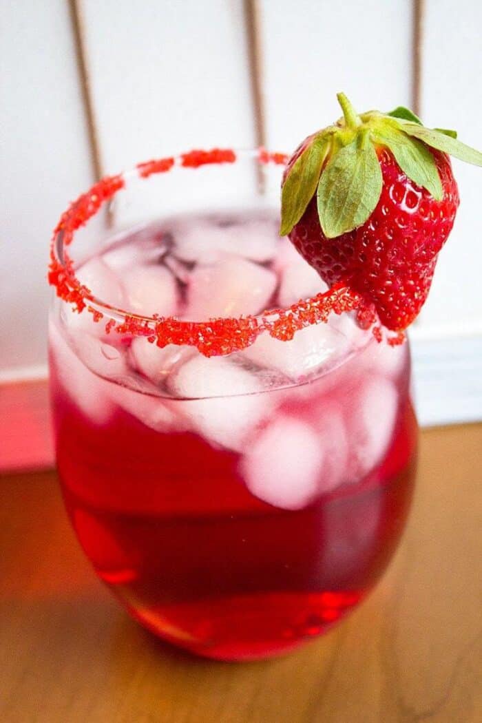 Valentine's Day Cocktail in cocktail glass with rim dipped in red sugar garnished with a fresh strawberry