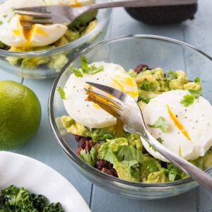 Kale Breakfast in transparent bowls topped with poached eggs on top