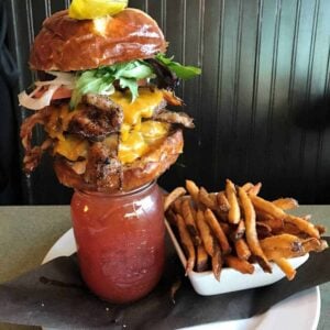 Bacon Double Alberta Beef Burger on top of a Bacon Caesar with fries on the side