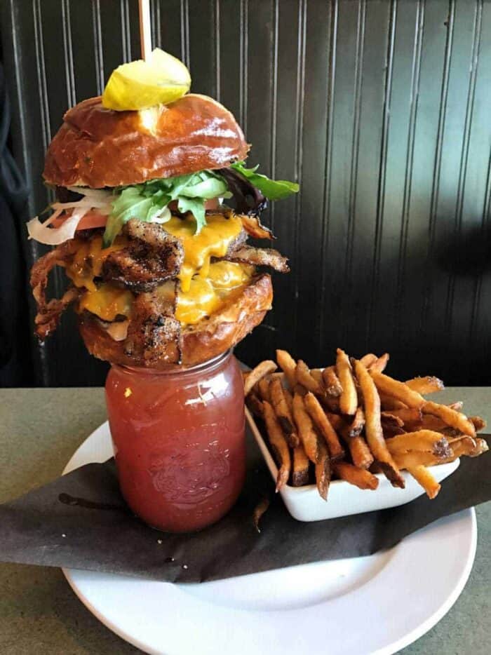 Bacon Double Alberta Beef Burger on top of a Bacon Caesar with fries on the side