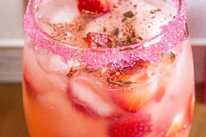 close up of Cupid's Arrow cocktail in a Glass with rim dipped in red sugar crystals