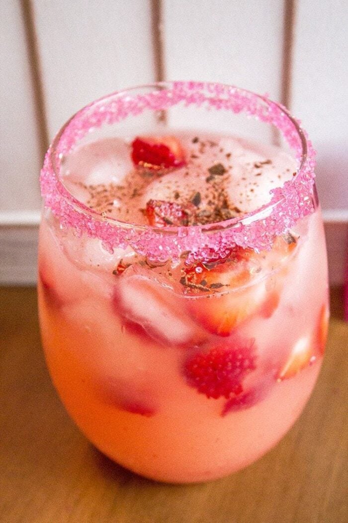 close up of Cupid's Arrow cocktail in a Glass with rim dipped in red sugar crystals