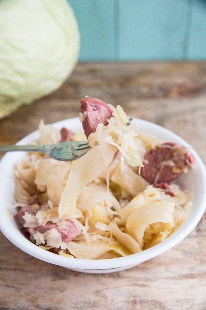 Close up of fork with sausage and cabbage from a bowl with Kielbasa Kapusta