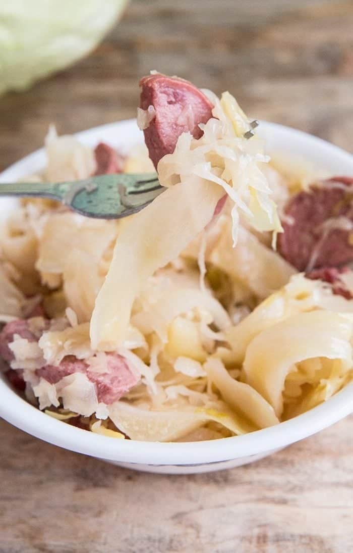 Close up of fork with sausage and cabbage from a bowl with Kielbasa Kapusta