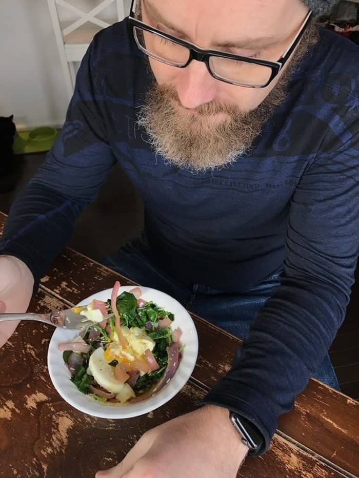 A man having his breakfast with a bowl of vegetables with egg