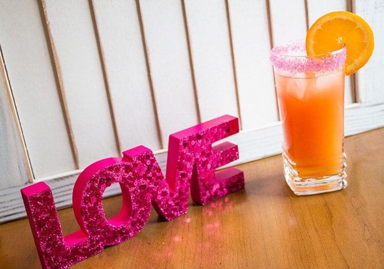 A Glass of Sex on the Beach Cocktail Garnish with Orange Slice, Pink LOVE lettering beside it