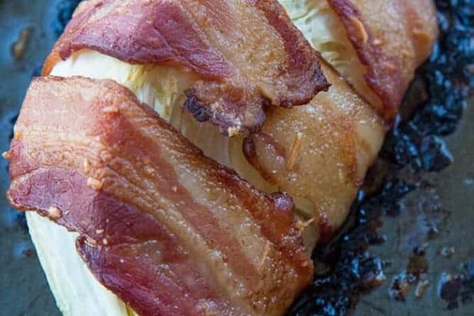 close up piece of Roasted Cabbage Wrapped in Bacon on a large baking sheet