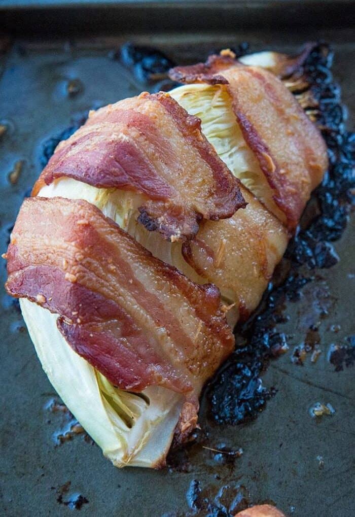 close up piece of Roasted Cabbage Wrapped in Bacon on a large baking sheet