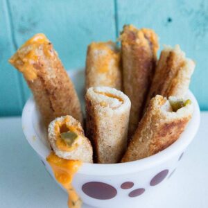 Jalapeno Grilled Cheese Rollups in a White Pyrex bowl with Circle prints on blue background