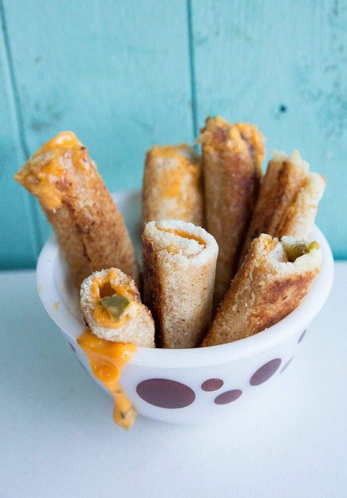 Jalapeno Grilled Cheese Rollups in a White Pyrex bowl with Circle prints on blue background