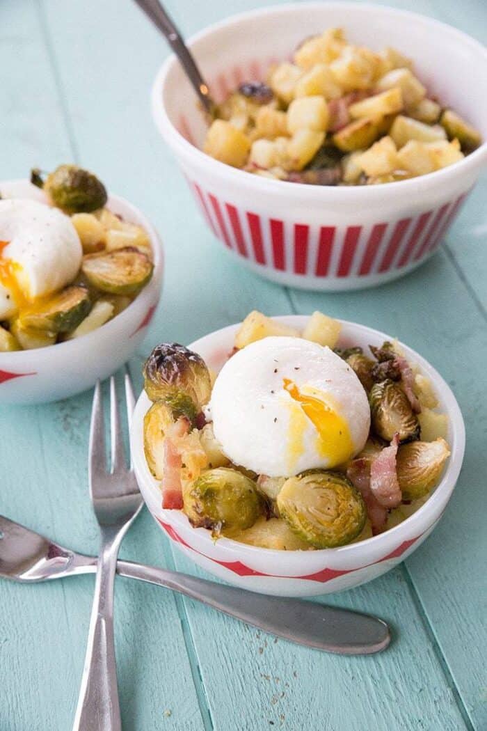 Close up of Roasted Brussels Sprouts, White Sweet Potato & Bacon Goal Bowls, two forks on the side