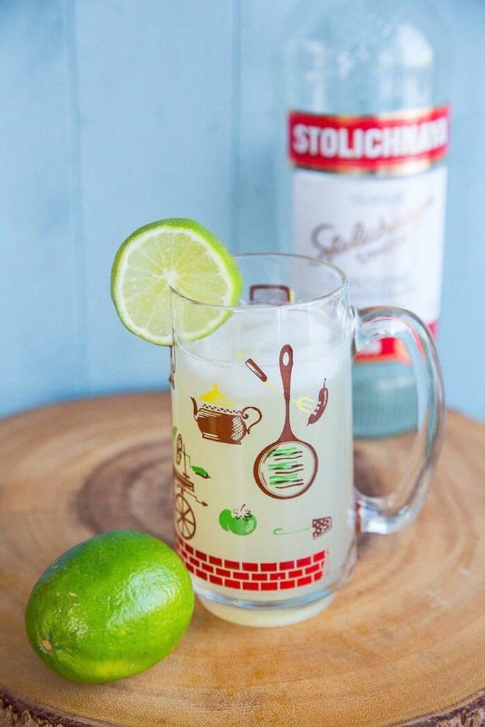 Classic Moscow Mule Recipe in a Vintage Hazel Atlas Glass, garnish with a slice of lime and a bottle of vodka on background