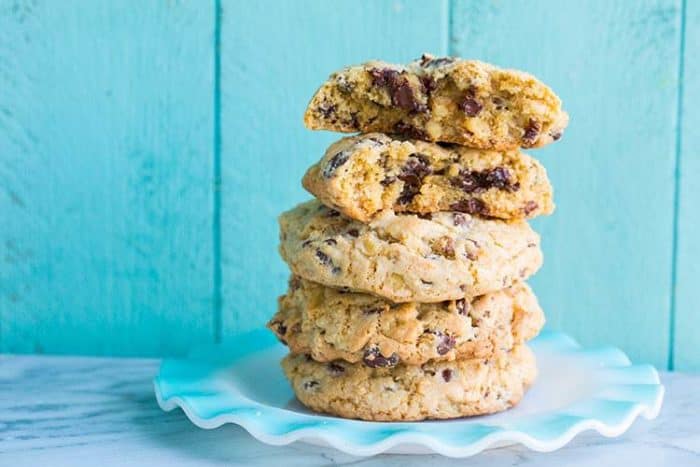 Stack of Walnut Loaded Chunky Chocolate Chip Cookies in Ruffle Plate on Blue Background